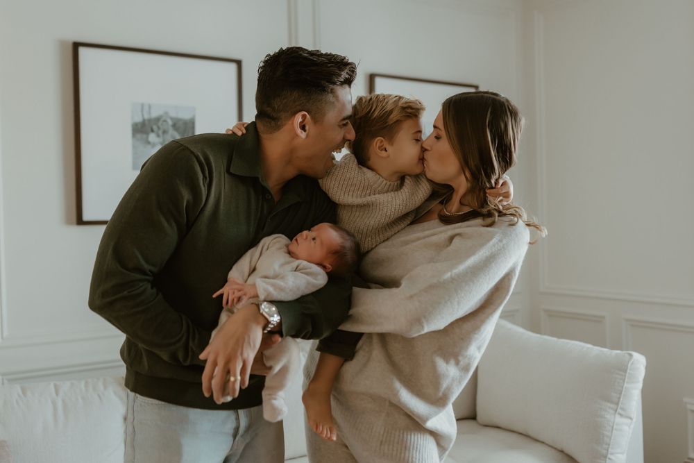 Intimate family moment shared on a white couch in a cozy living room with warm lighting.