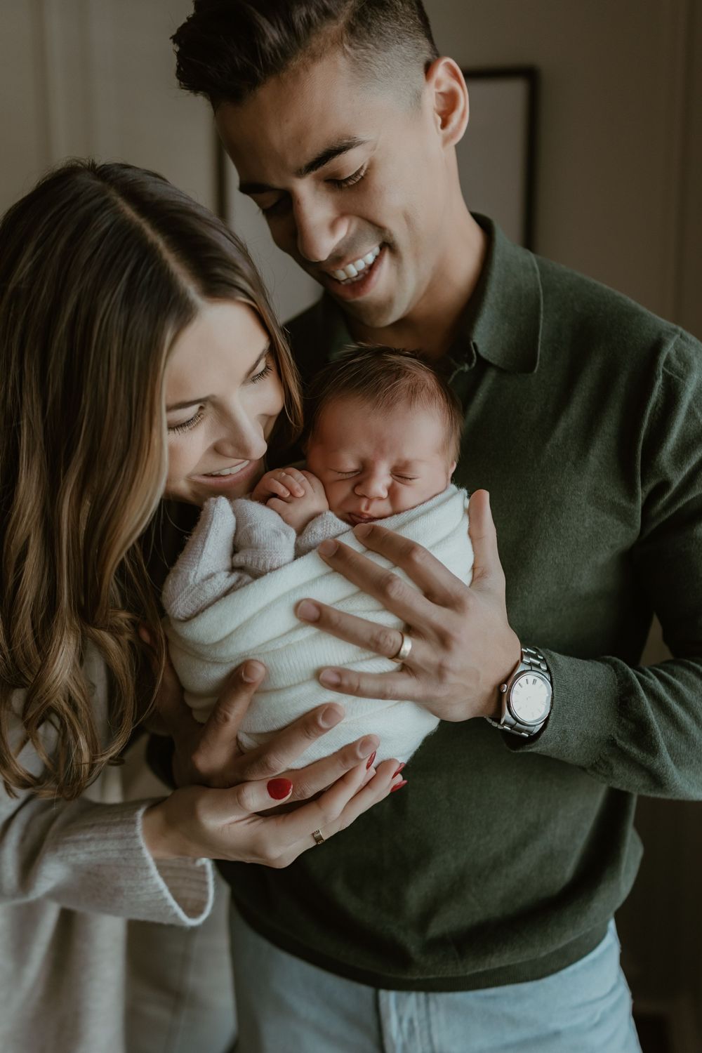A tender family moment as parents cradle and kiss their newborn baby in a series of intimate portraits.