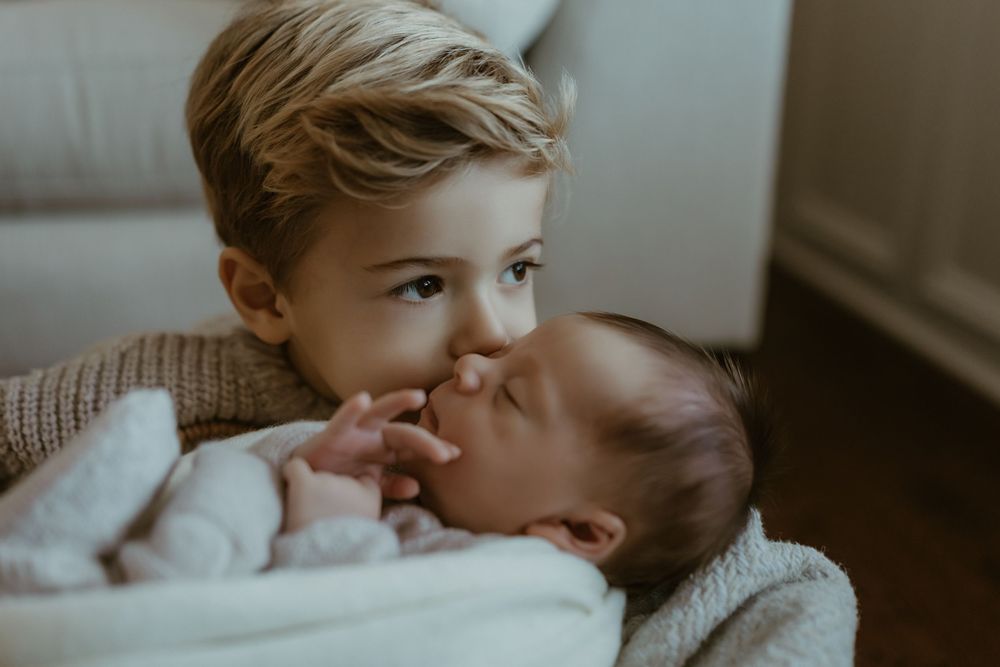 An intimate family moment as they gaze lovingly at their newborn baby wrapped in white.