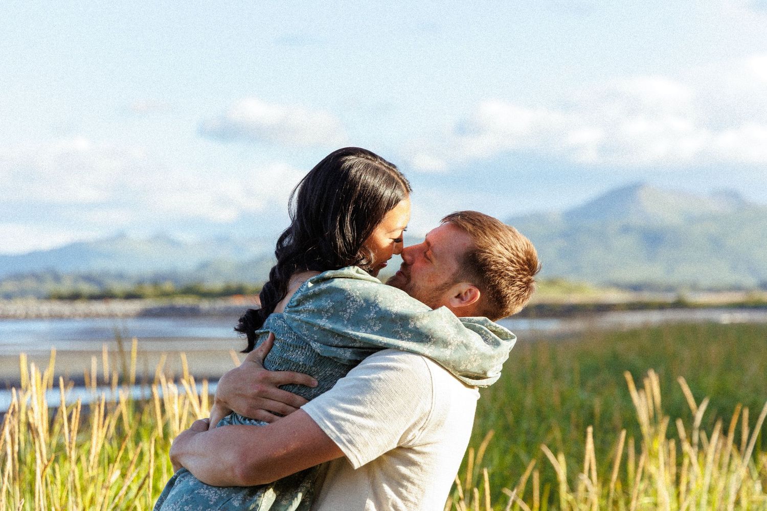 Romantic moment captured in golden sunlight with mountain backdrop.