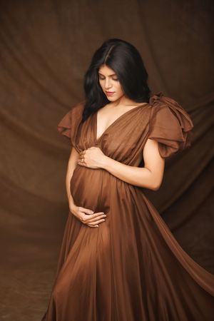 Multiple artistic pregnancy photos featuring a brown empire-waist dress against a dark background.
