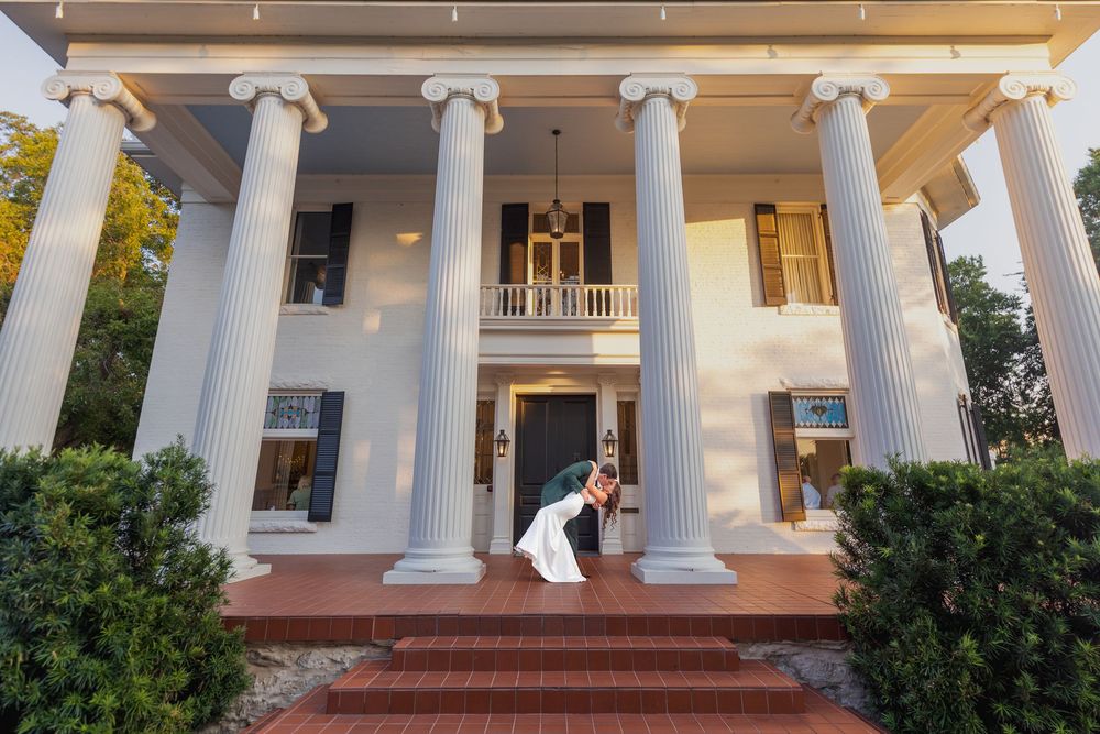 Elegant southern mansion with tall white columns and red brick steps features a grand entrance with classic architecture.