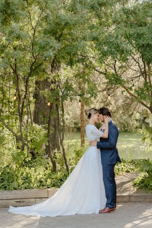 A romantic woodland wedding scene with flowering trees and lush greenery surrounding a garden path.