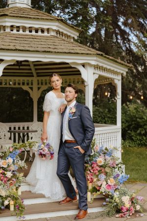 Romantic gazebo setting decorated with colorful floral arrangements for a garden wedding.
