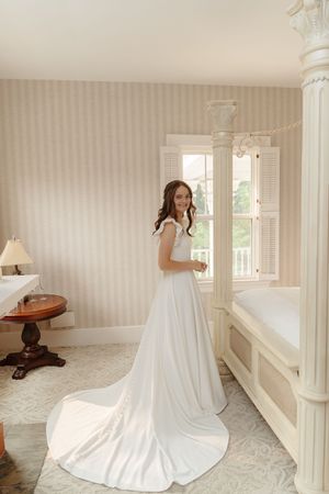 Elegant white wedding dress with a dramatic long train displayed in a bright interior room.