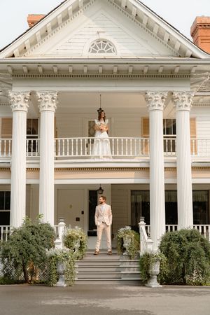 Elegant white colonial mansion with tall columns and a covered porch creates a grand wedding venue entrance.