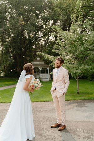 A romantic first look moment unfolds on a garden path with lush greenery surrounding the couple.