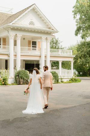 Elegant white colonial mansion with tall columns serves as backdrop for romantic wedding couple portraits.
