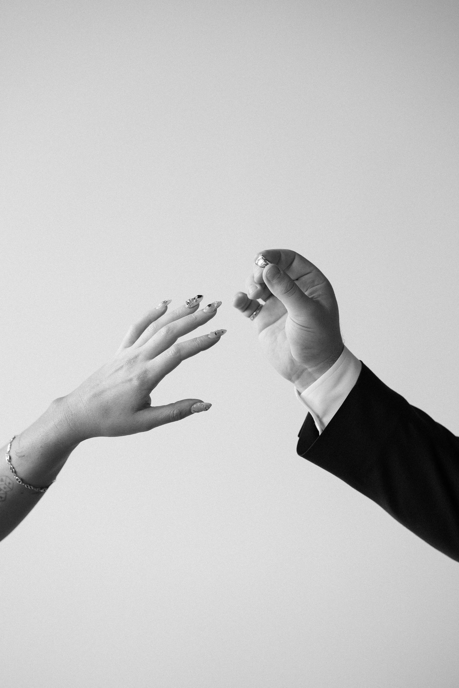 Black and white close-up of a groom placing an engagement ring on his brides outstretched hand. Victoria, BC, Vancouver Island.