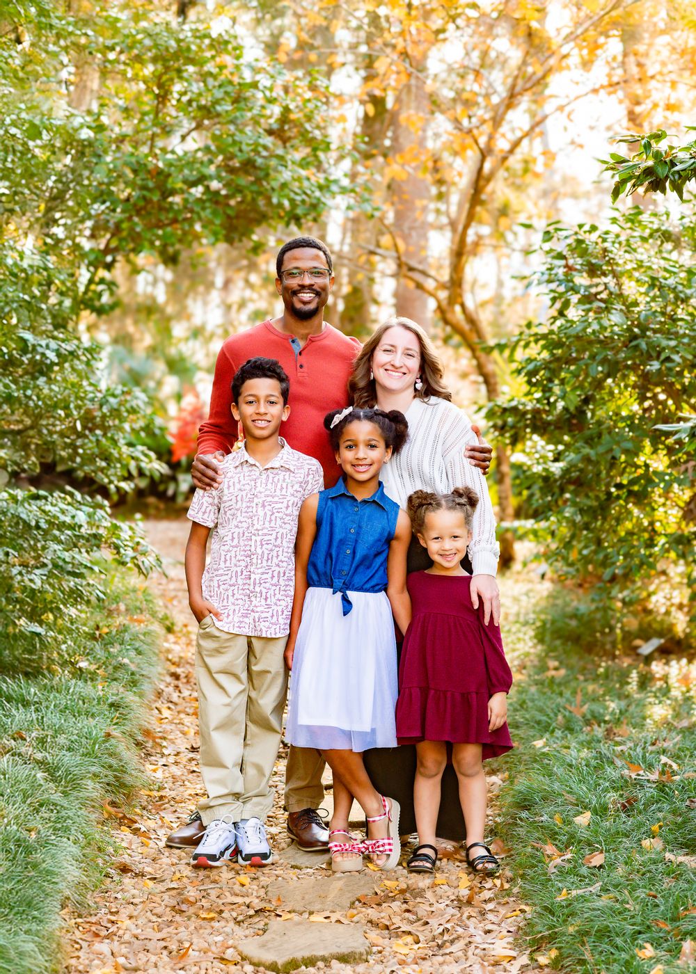 A happy group enjoying a sunny autumn day together on a leaf-covered forest path.