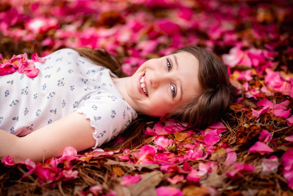 Young girl lying in a bed of colorful flowers, capturing a serene and joyful moment