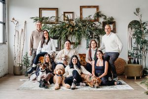 Group of dogs and their owners sitting together in a bright, modern studio space.