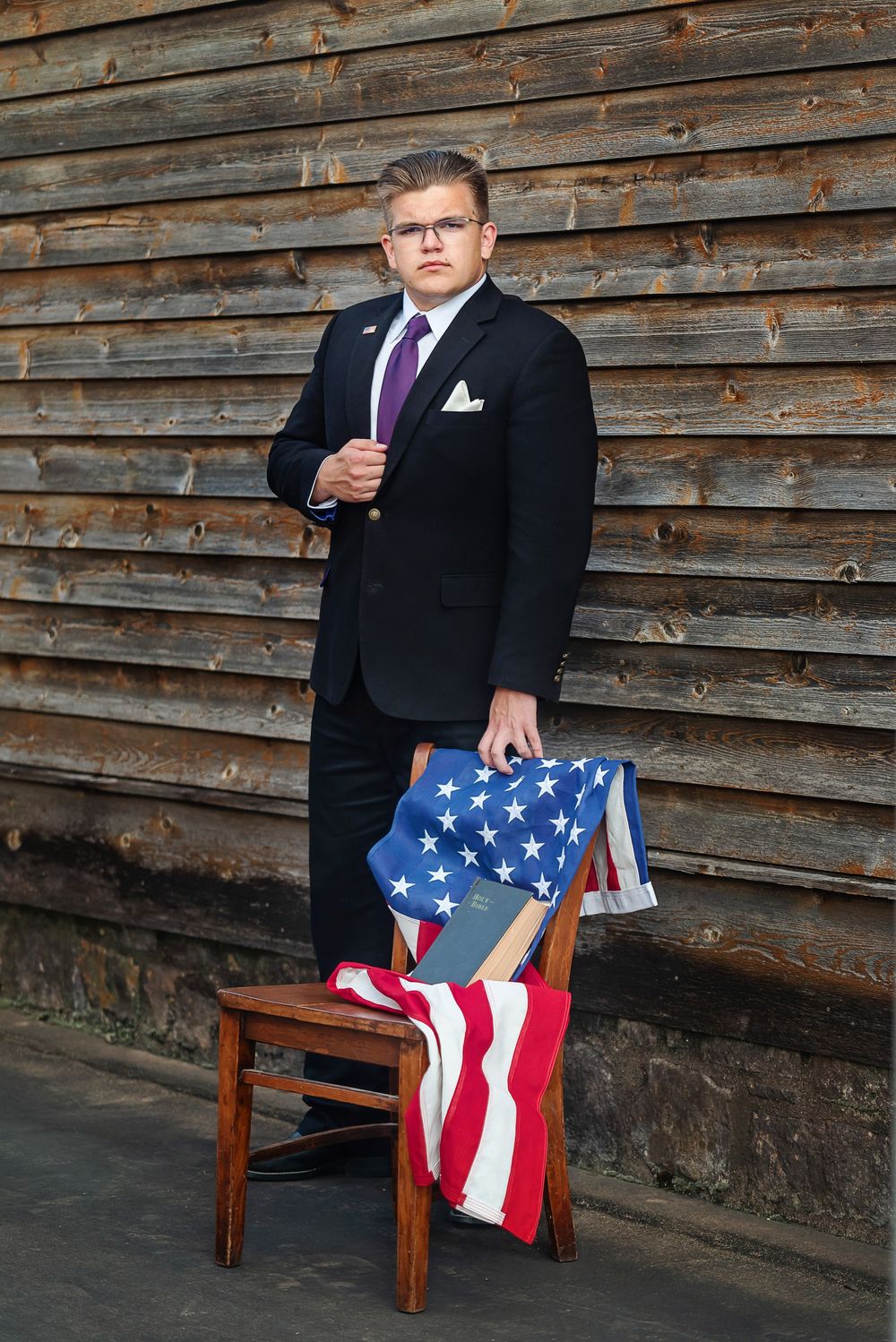 senior wearing suit and posing with American flag and Bible