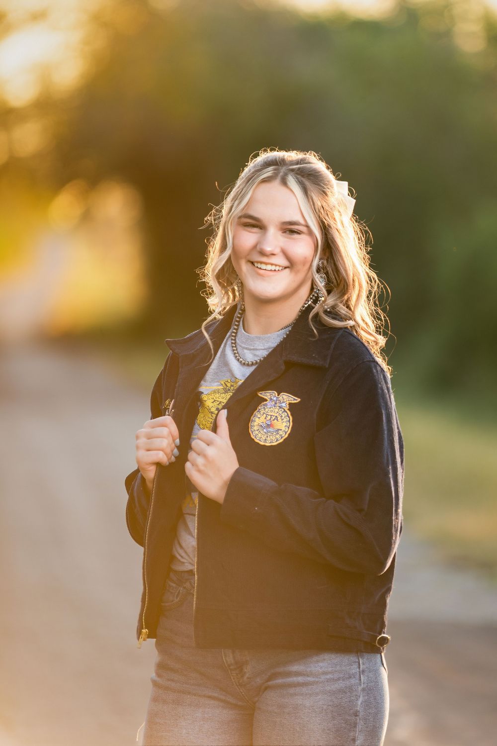 senior FFA girl wearing jacket and smiling at sunset