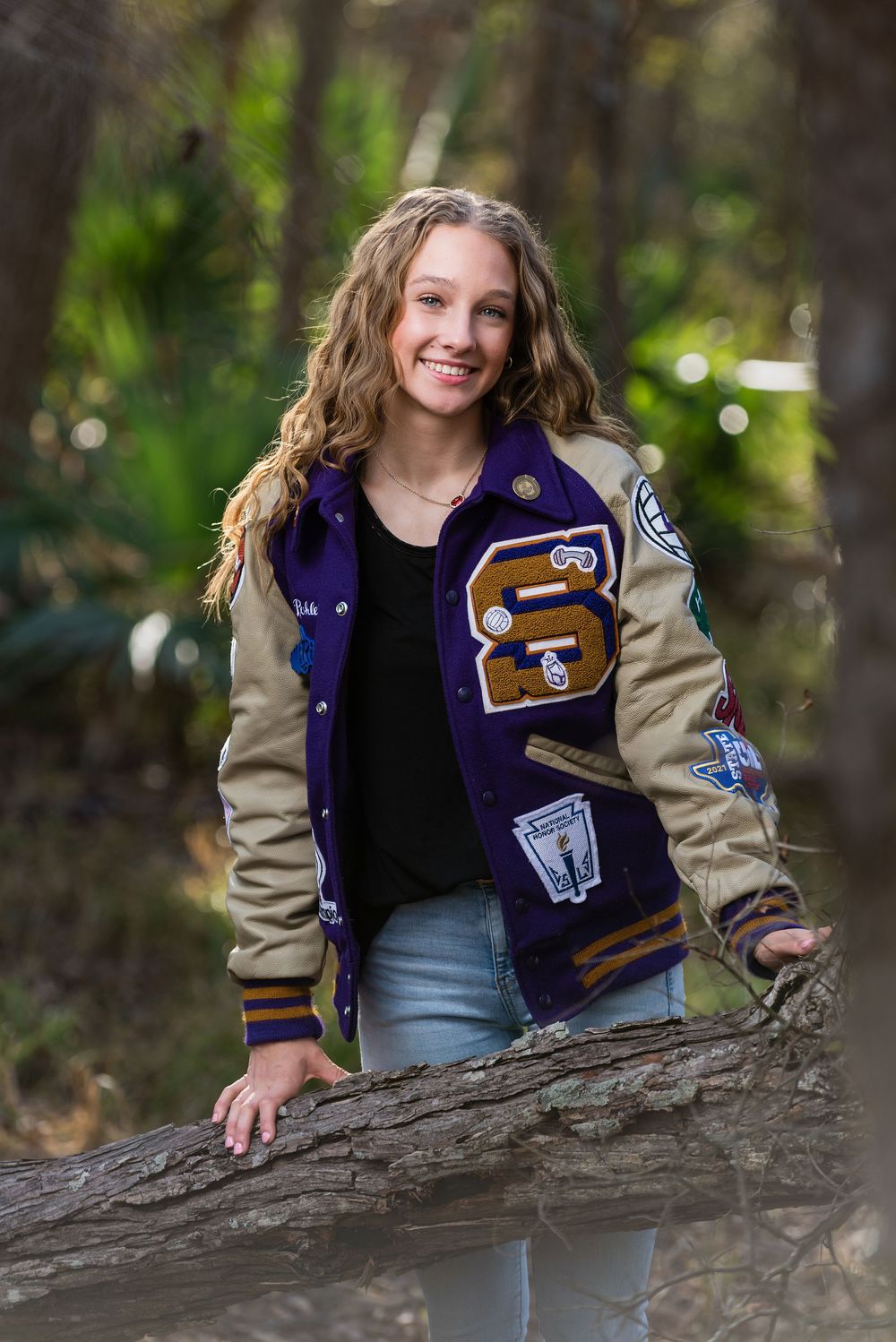 Senior girl smiling outdoor while wearing letterman jacket