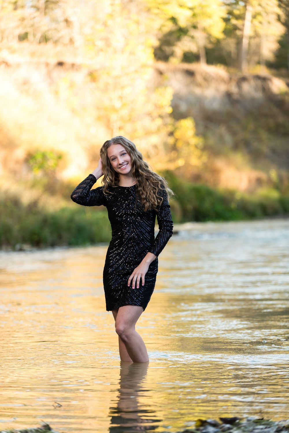 Senior girl smiling in river at sunset