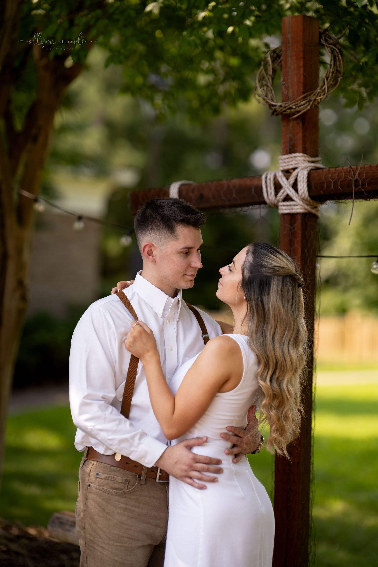 Intimate moment between couple by wooden cross in garden setting.