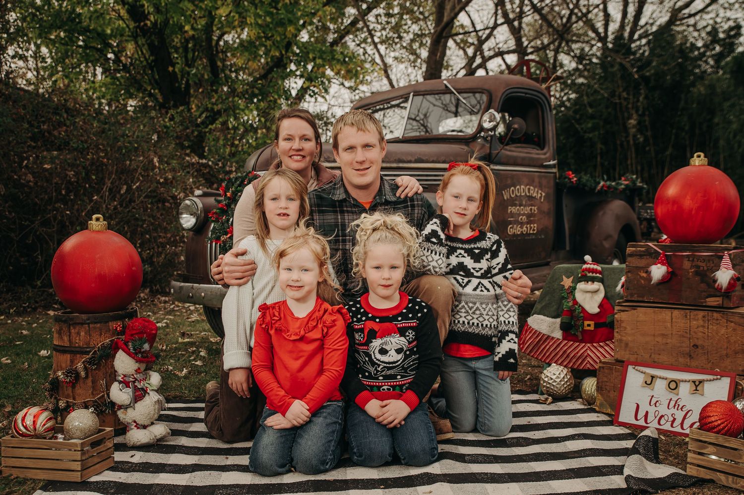 Holiday family photo session with festive decorations and pumpkins on a striped blanket.