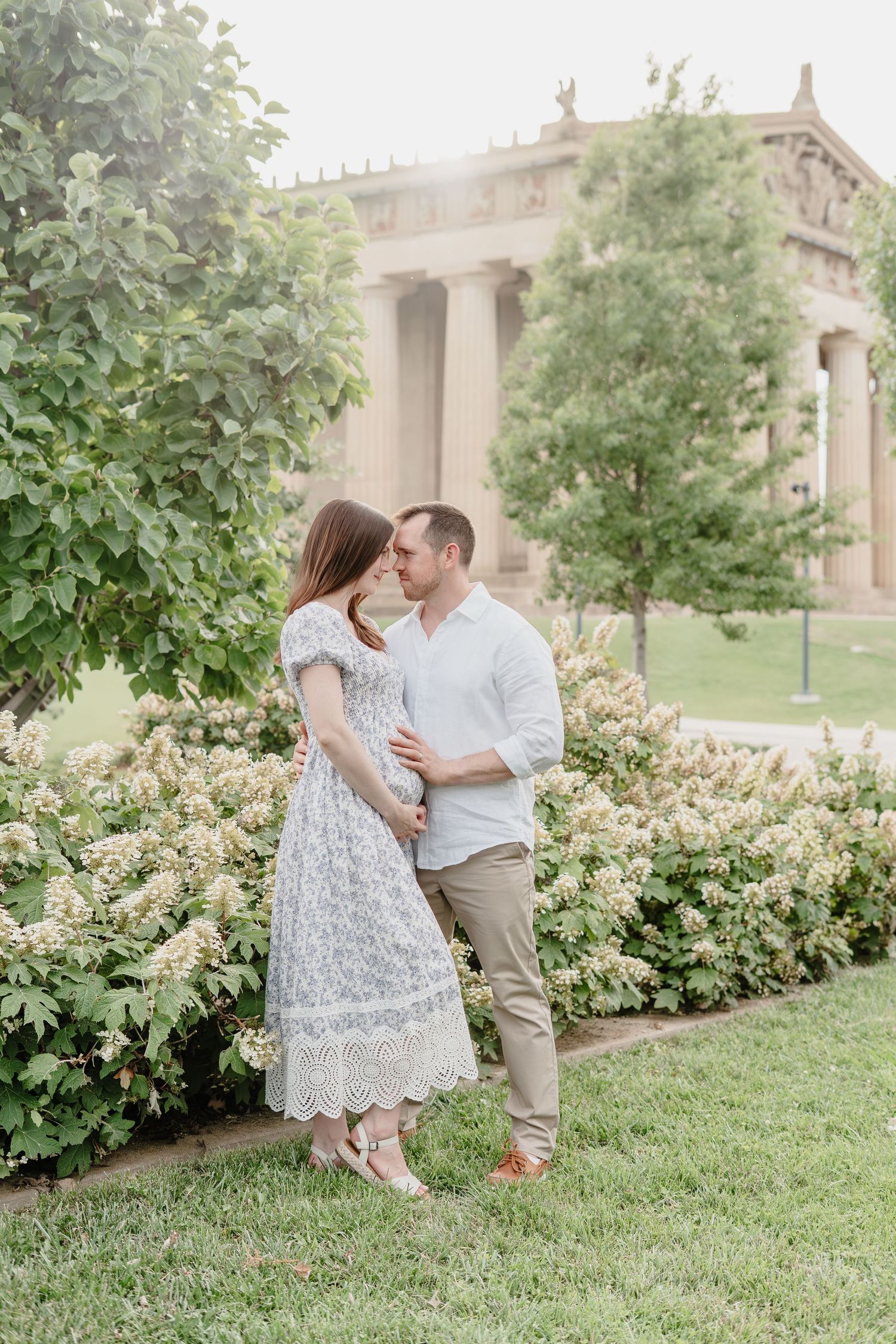A couple walks together on a sidewalk in front of a pink historic building with a grand white doorway.