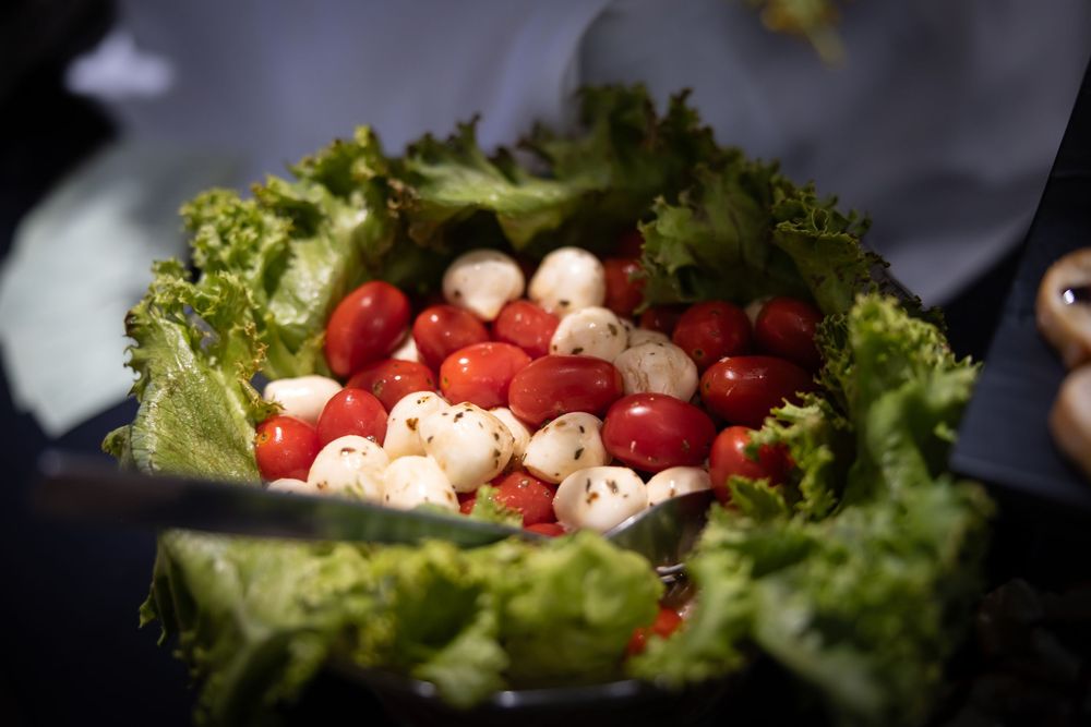 Fresh caprese salad ingredients arranged on green lettuce leaves with cherry tomatoes and mozzarella balls.