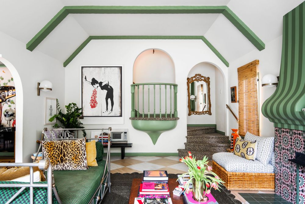 Bohemian living room with green accents, leopard pillows, and arched doorways features artistic wall decor.