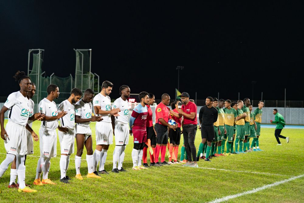 Équipes de football alignées sur le terrain avant un match en nocturne