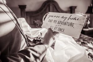 A black and white photograph shows a handwritten note with text about adventure resting on fabric.