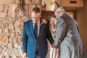 An emotional moment between three people during a celebration in a rustic stone-walled venue.
