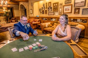Two players engaged in a poker game at a casino table with cards and chips in warm rustic interior setting.