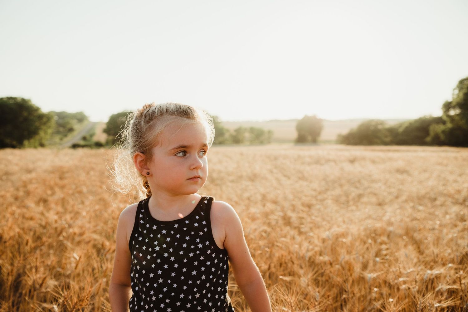 Young blonde girl in a Kansas wheat field in Concordia Kansas.