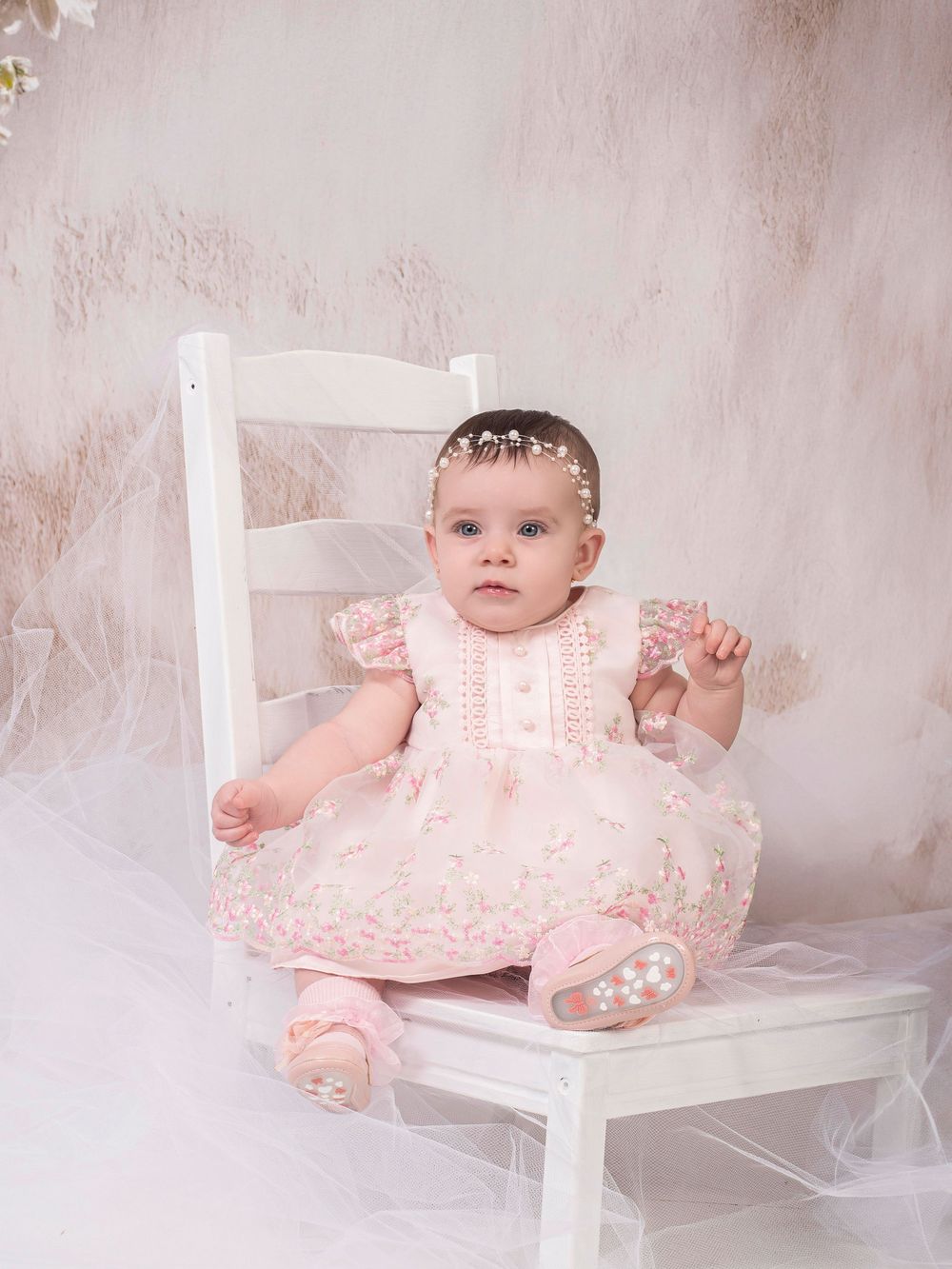 Set of baby portrait photographs featuring infants in pink lace dresses posing on white chairs against a soft pink background.