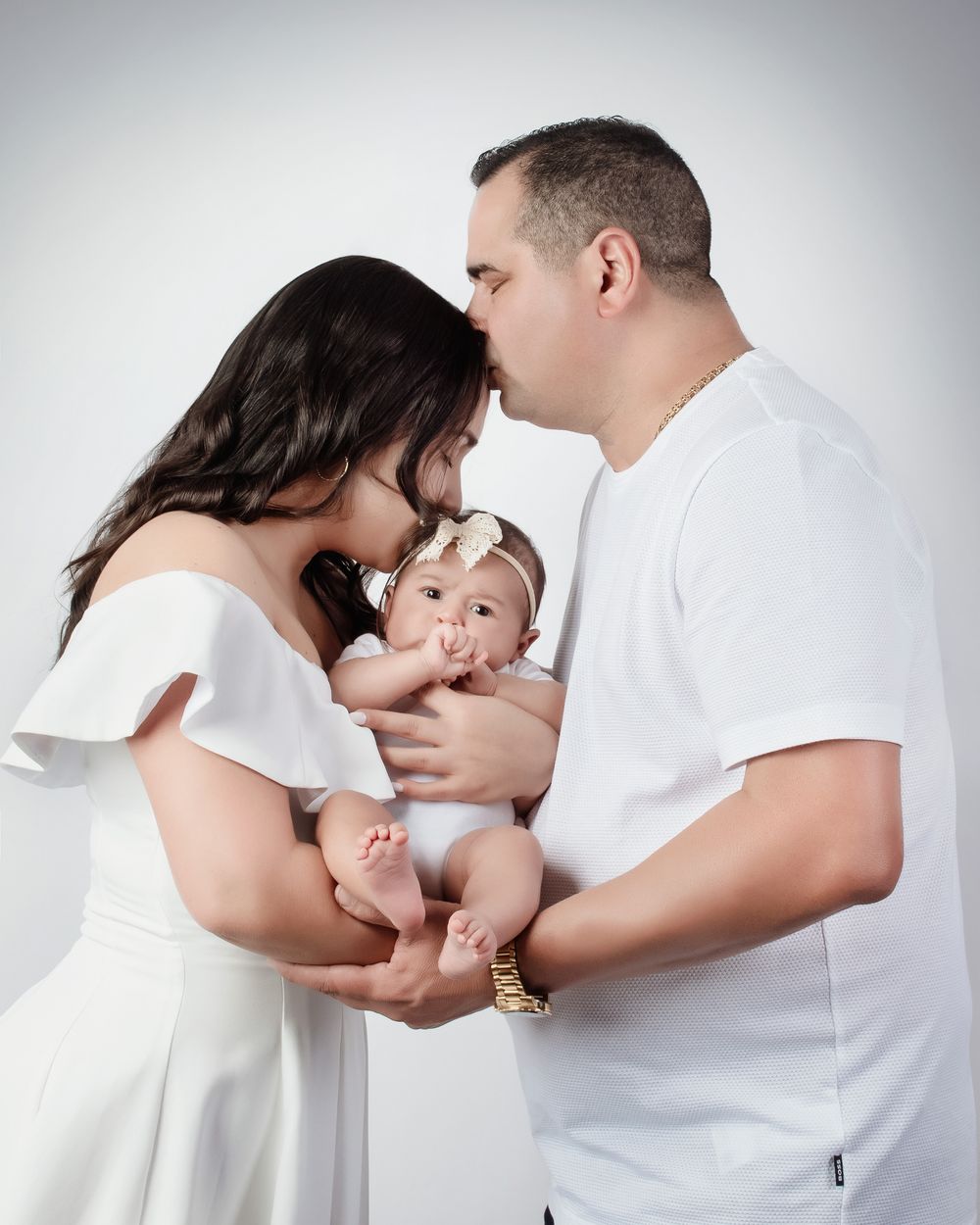 A family in white clothing hugging and showing affection in a sequence of connected photos against a light background.