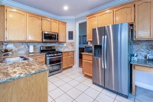 Updated kitchen with oak cabinets, granite countertops, stainless steel refrigerator, gas range, microwave, and tile flooring.