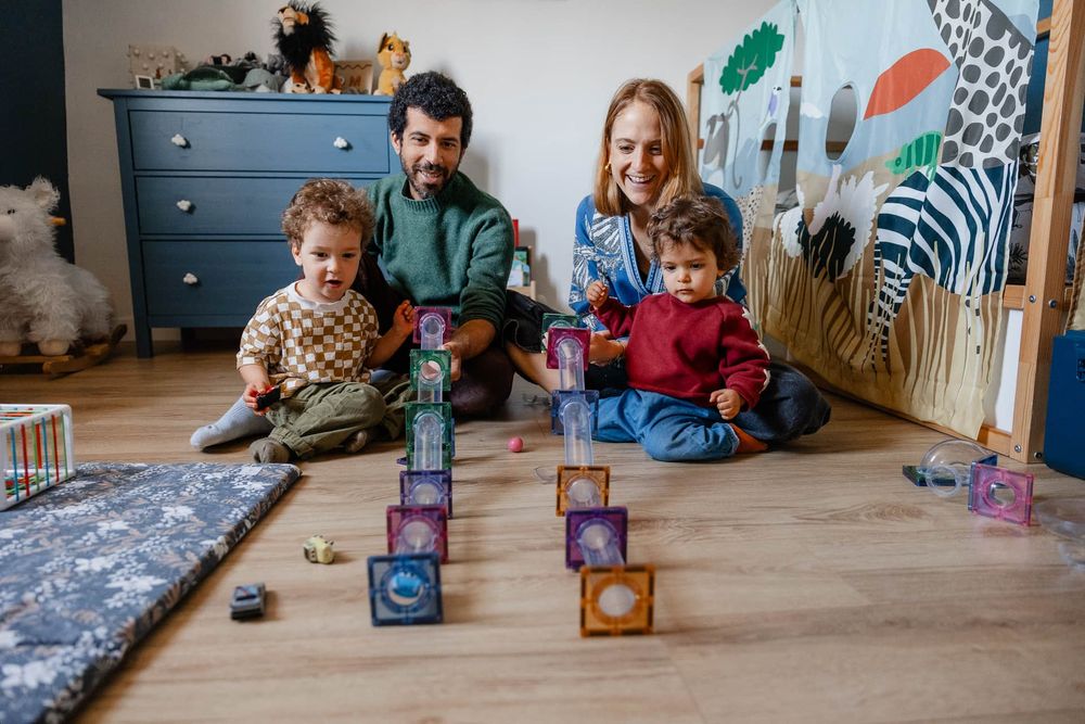 Famille joue au circuit de billes dans la chambre des enfants, un moment joyeux du quotidien capture en seance photo de famille a Lille