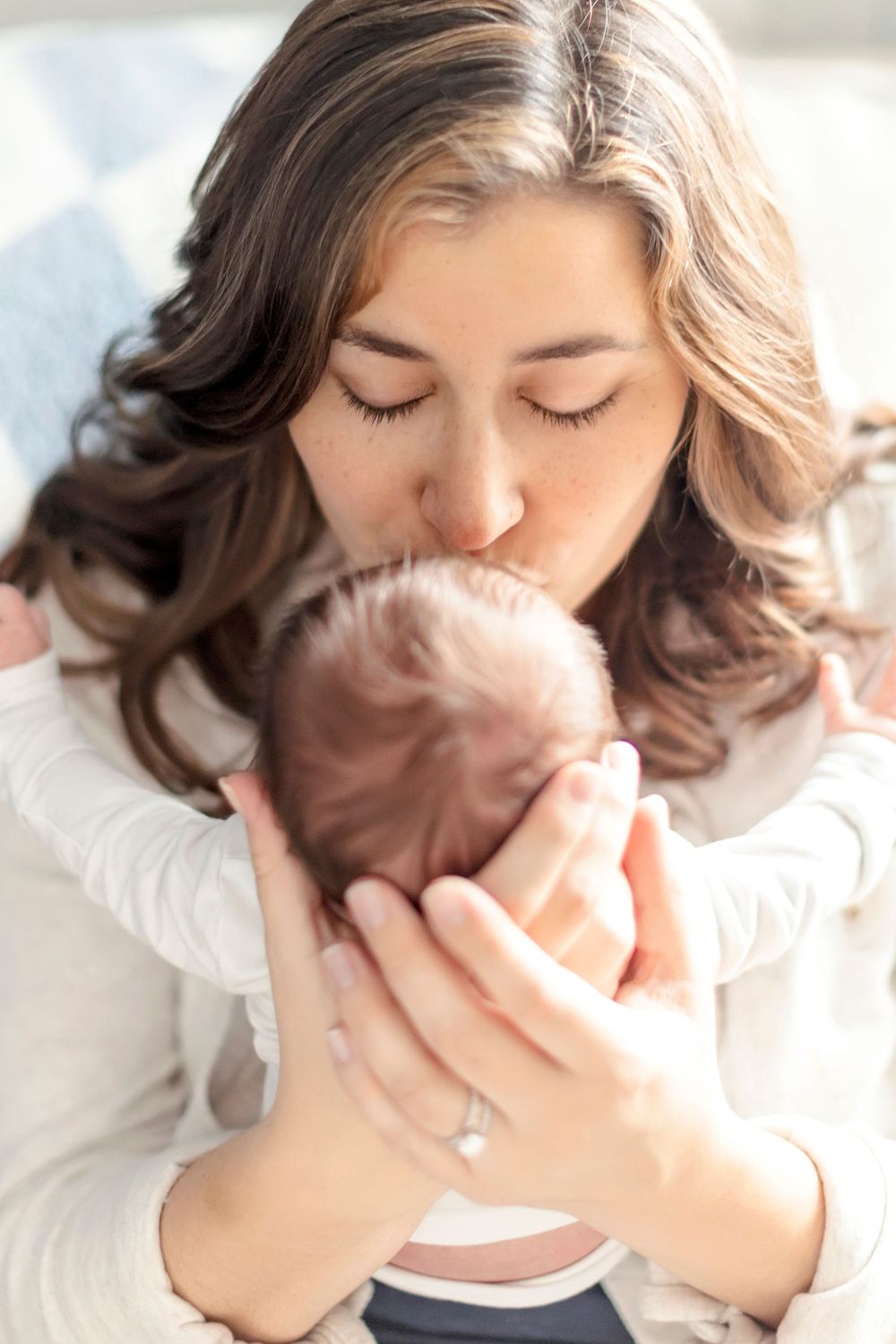 Close up of gentle moment with parent cradling newborn baby while wearing white sweater.