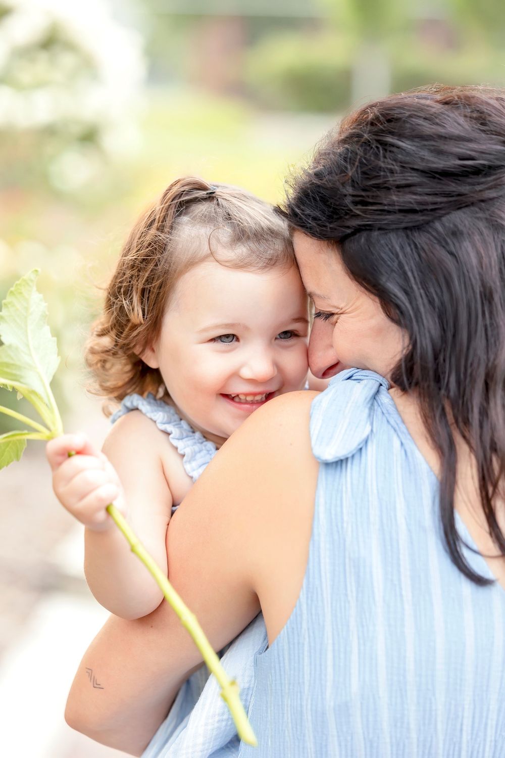 A tender moment shared between parent and child with a yellow flower against a soft blurred background.