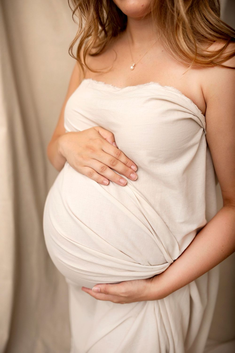 Maternity detail portrait with elegant drapery and soft neutral styling during a studio session in Clear Lake, Iowa
