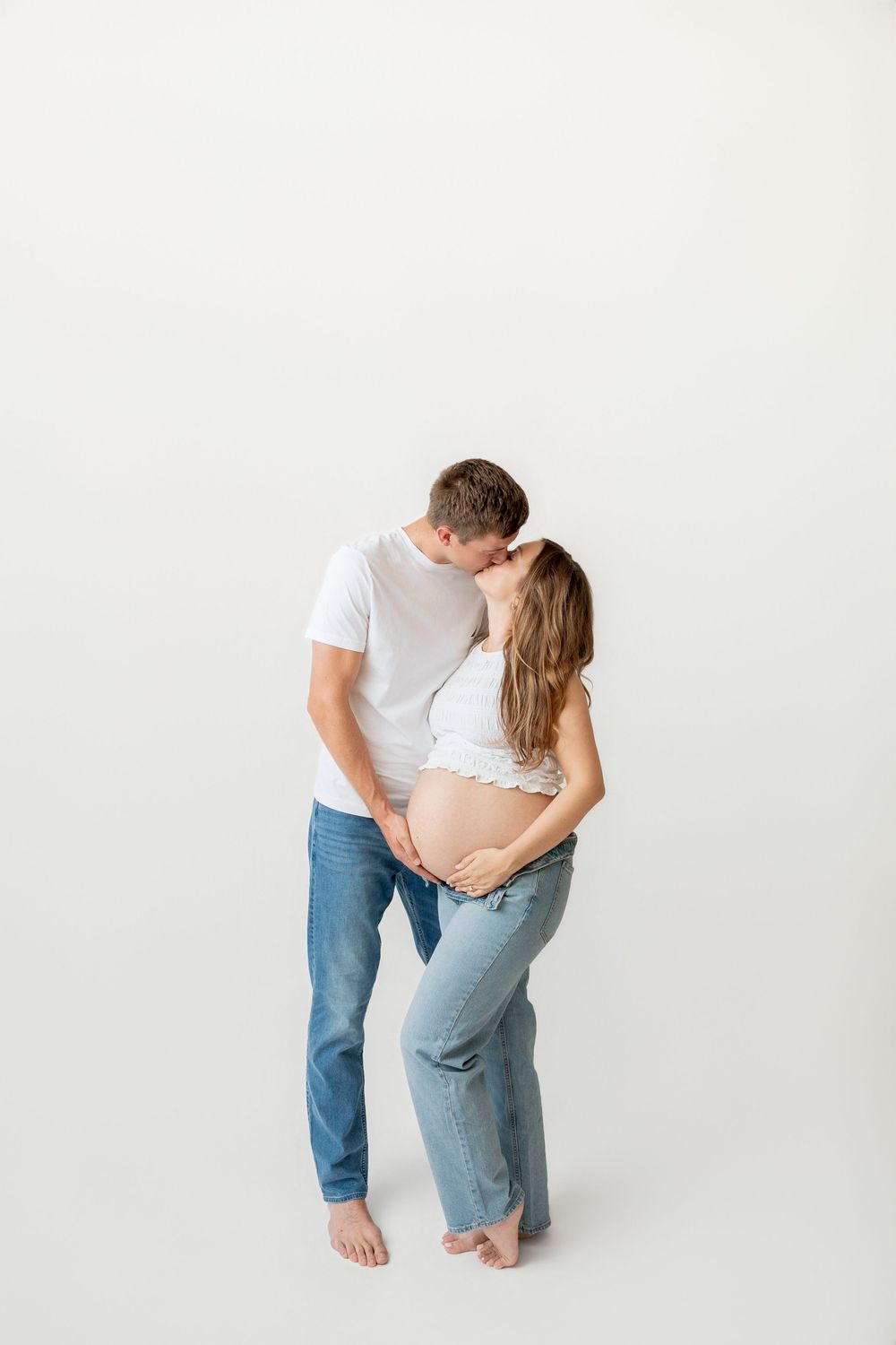 Pregnant couple kissing during a simple timeless studio maternity session in Clear Lake, Iowa