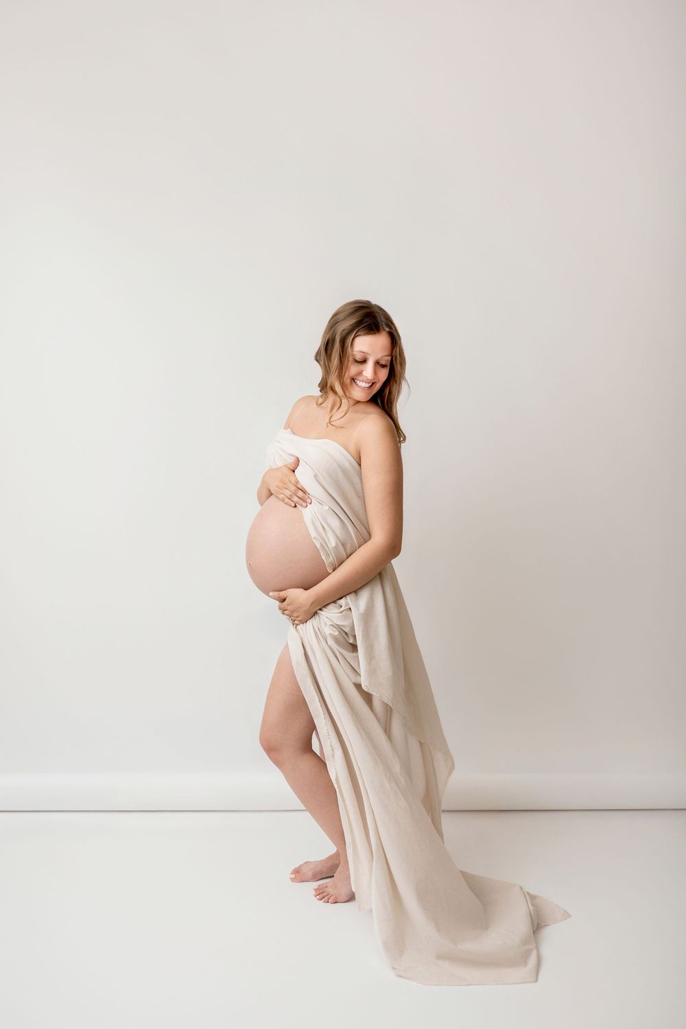Elegant editorial maternity portrait in a neutral draped gown at a Clear Lake, Iowa studio