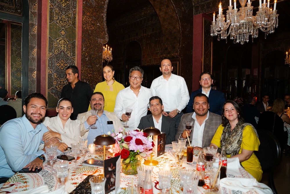 A group of people dining together at an elegant restaurant table under crystal chandeliers.