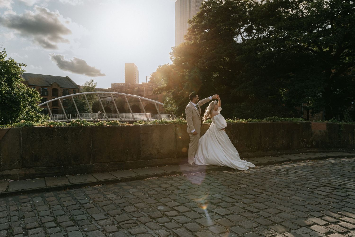 Urban architectural landscape with repeating arches and cobblestone ground at sunset.