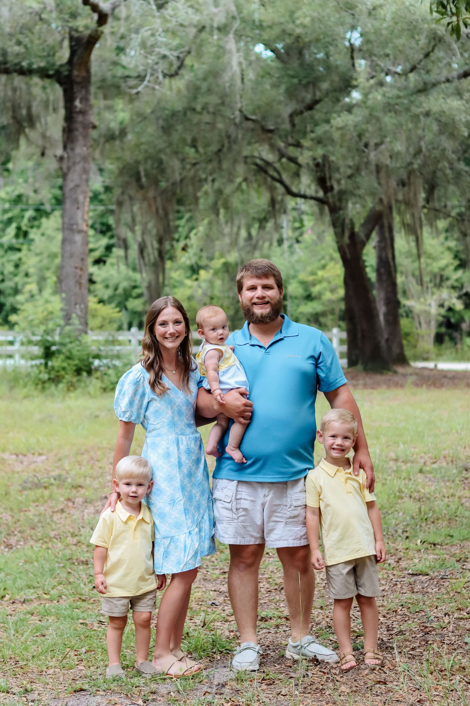 A family portrait under moss-draped oak trees in a Southern park setting.