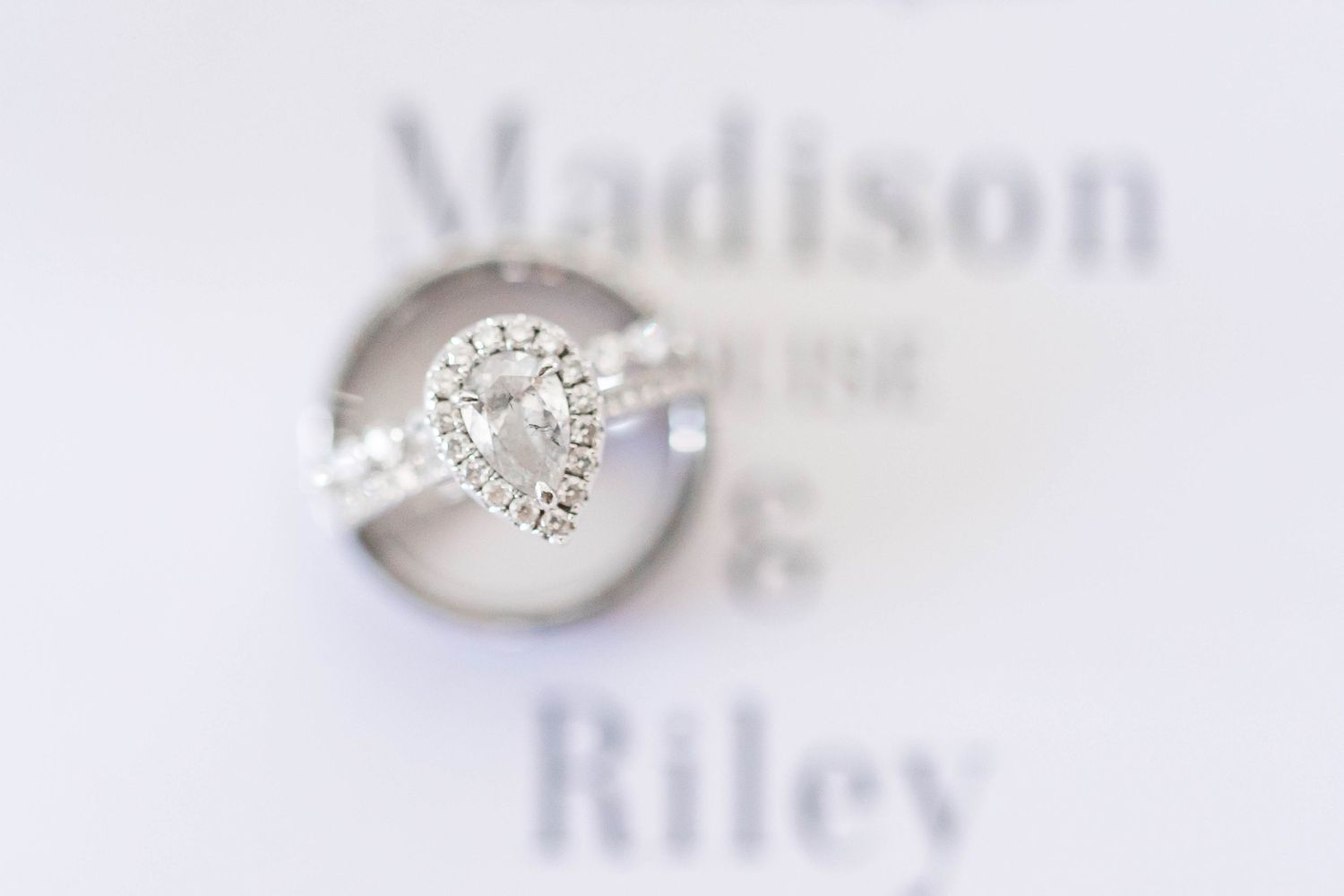 Close-up of elegant heart-shaped diamond engagement ring with names in background.