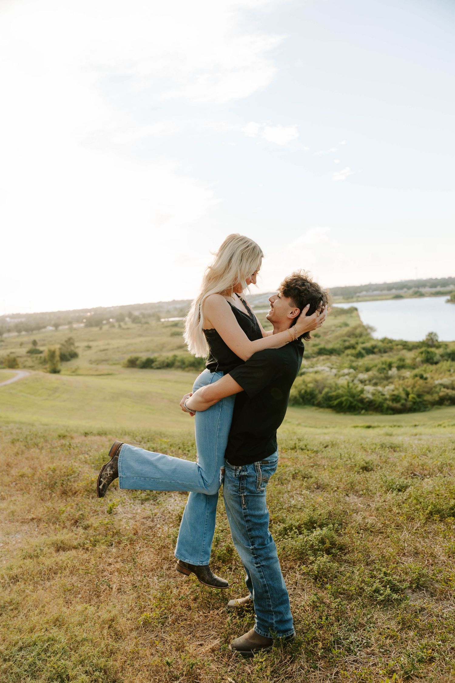 A tender moment between a couple in casual attire standing in a golden field.