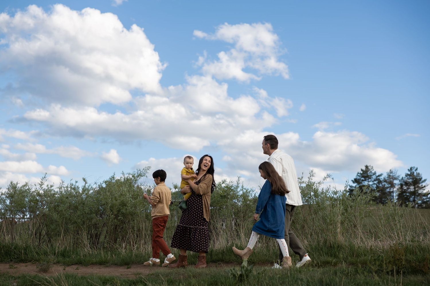 Sioux City, Iowa photographer. Family of three standing on a quiet road in autumn, parents holding child's hands.