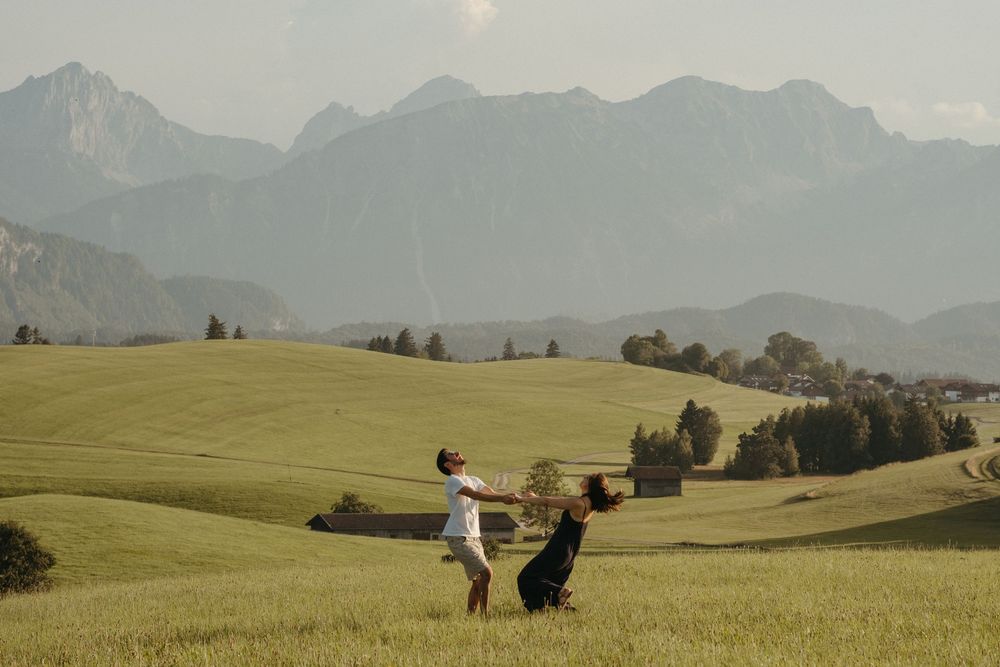 International  Couple having fun in the green field with mountains in Bavaria
