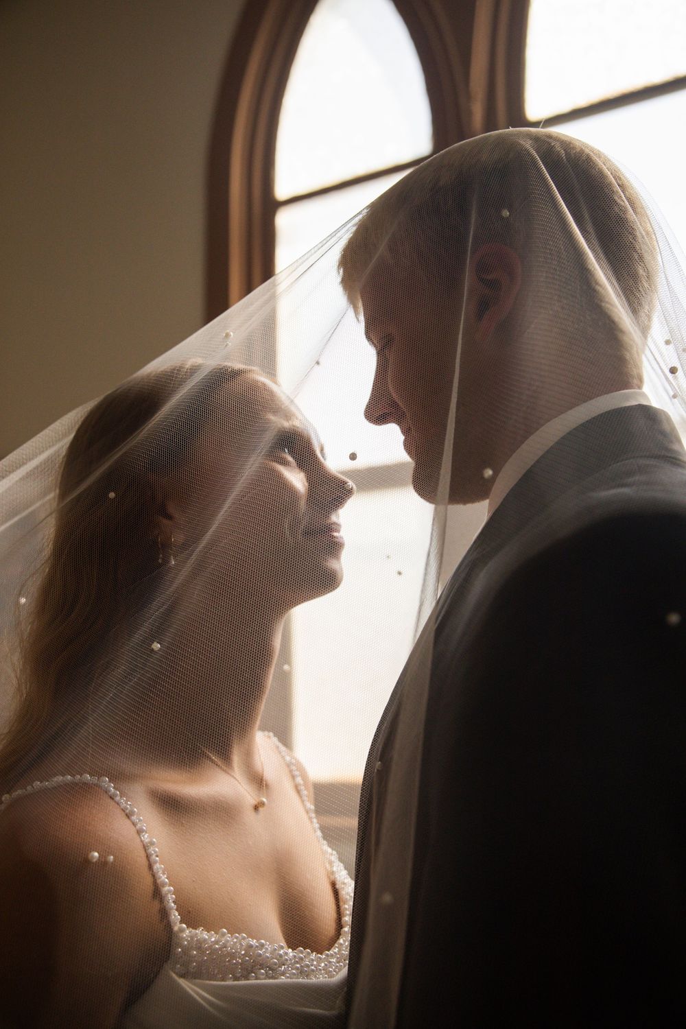 Artistic sequence of a bride in a white wedding dress and veil illuminated by soft window light.