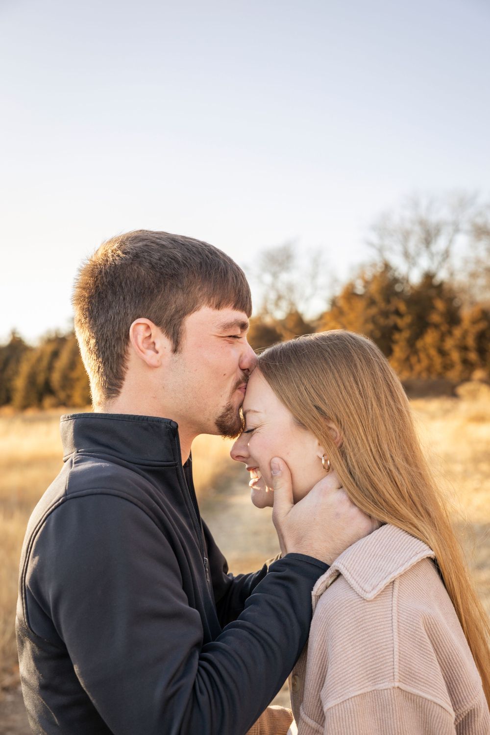 Intimate couple moment captured during sunset in autumn field setting.