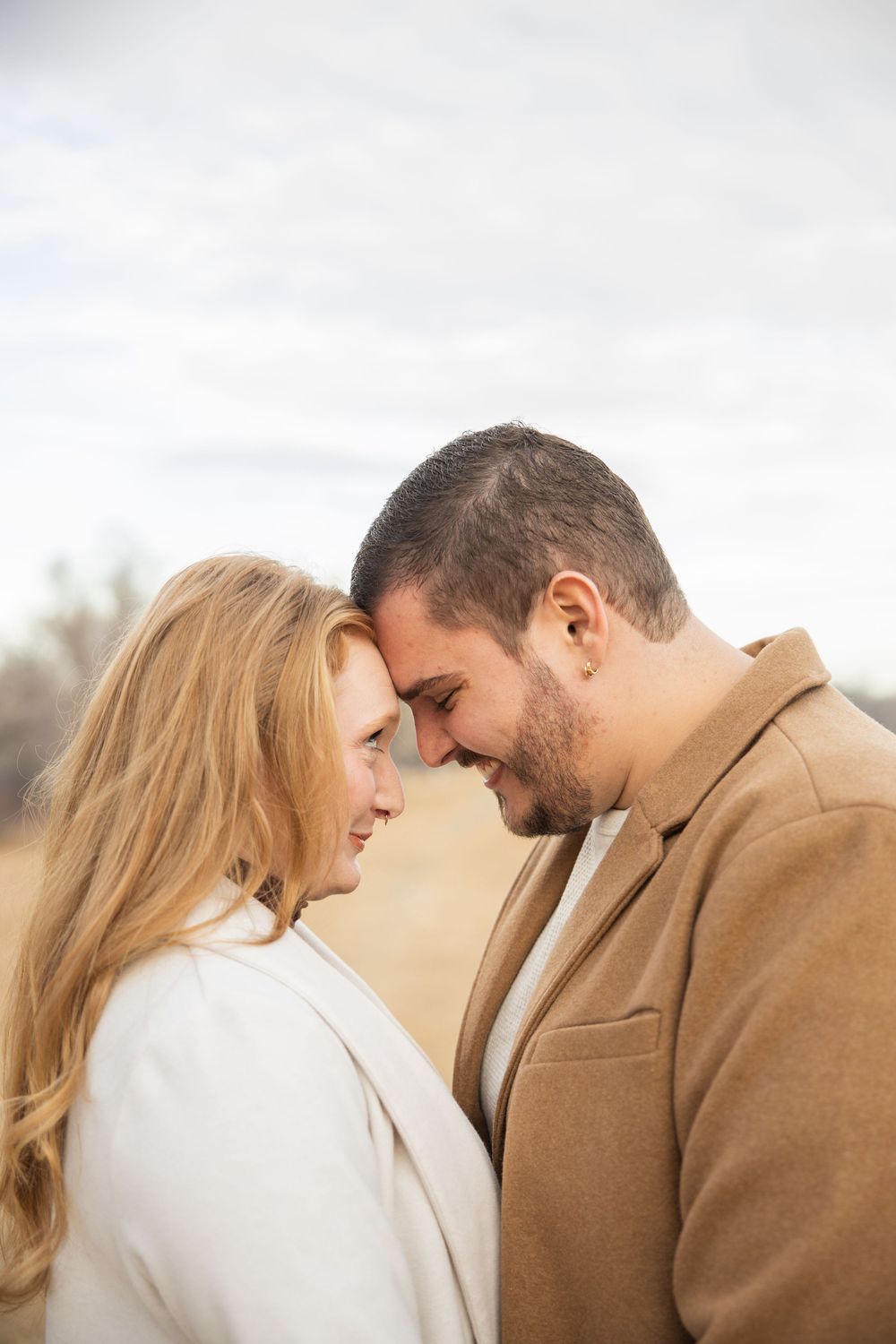Romantic couple in winter coats sharing intimate moment outdoors.