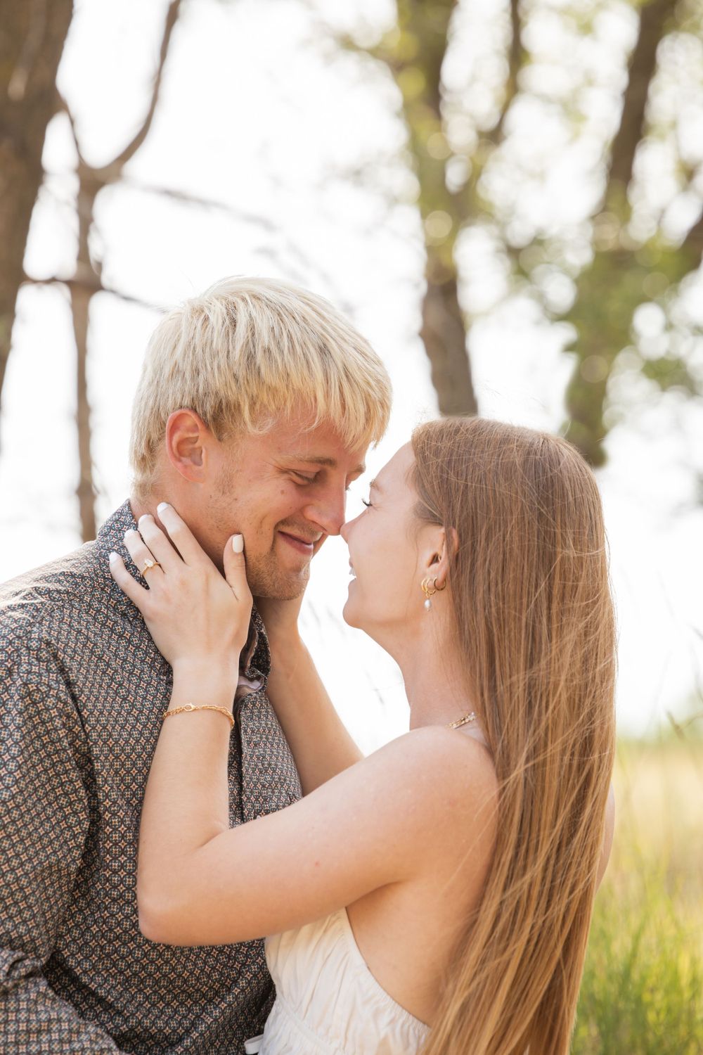Romantic couple sharing intimate moment in sunlit outdoor setting.